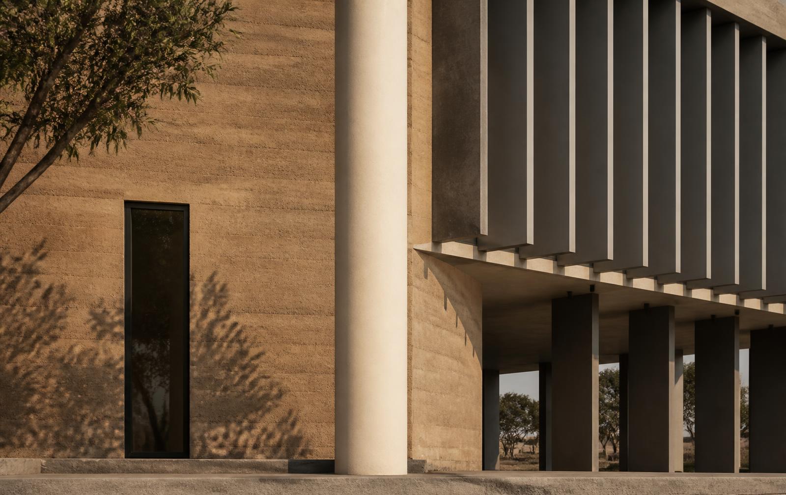 Rammed-earth civic building facade in late afternoon light